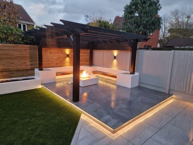 an outdoor fire pit in the middle of a yard with lights on it and grass