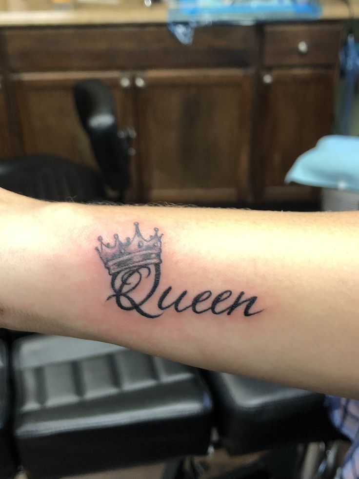 a woman's arm with a crown tattoo on it and the word queen written in cursive font