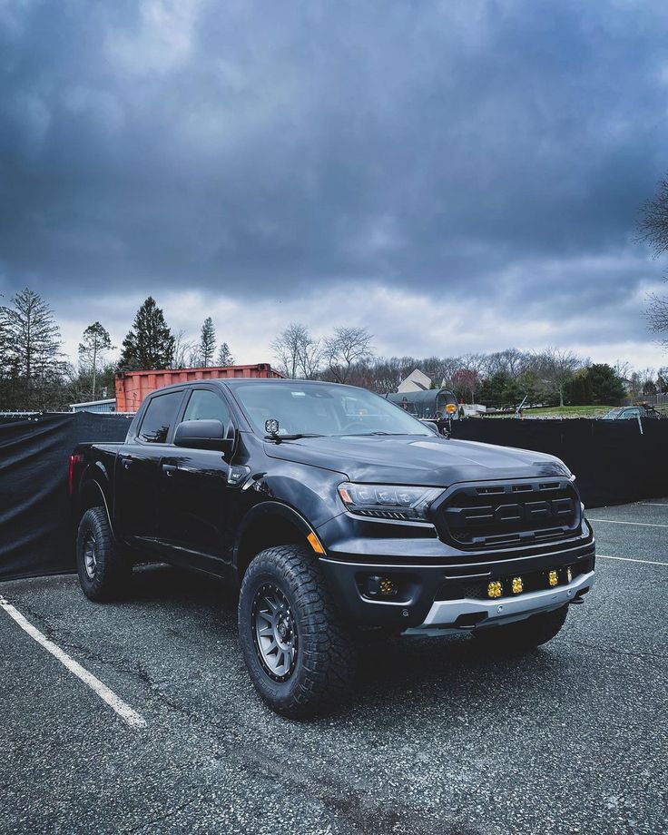 a black pickup truck parked in a parking lot under a cloudy sky with dark clouds