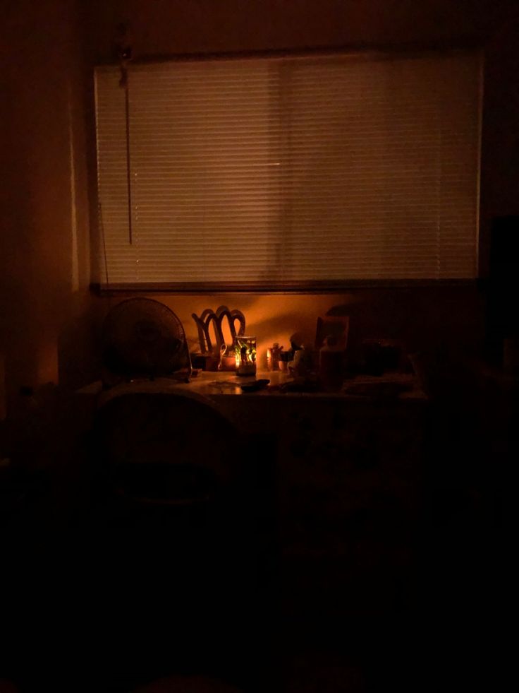 a dark room with the lights on and some chairs in front of a window that is lit up