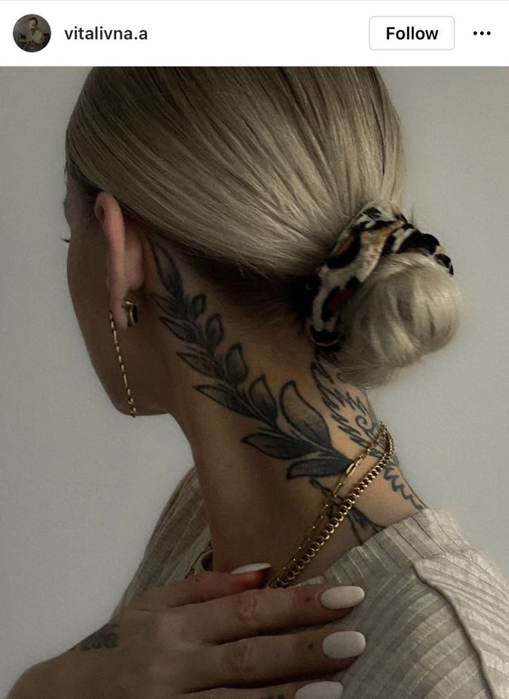 a woman with tattoos on her neck and behind her ear