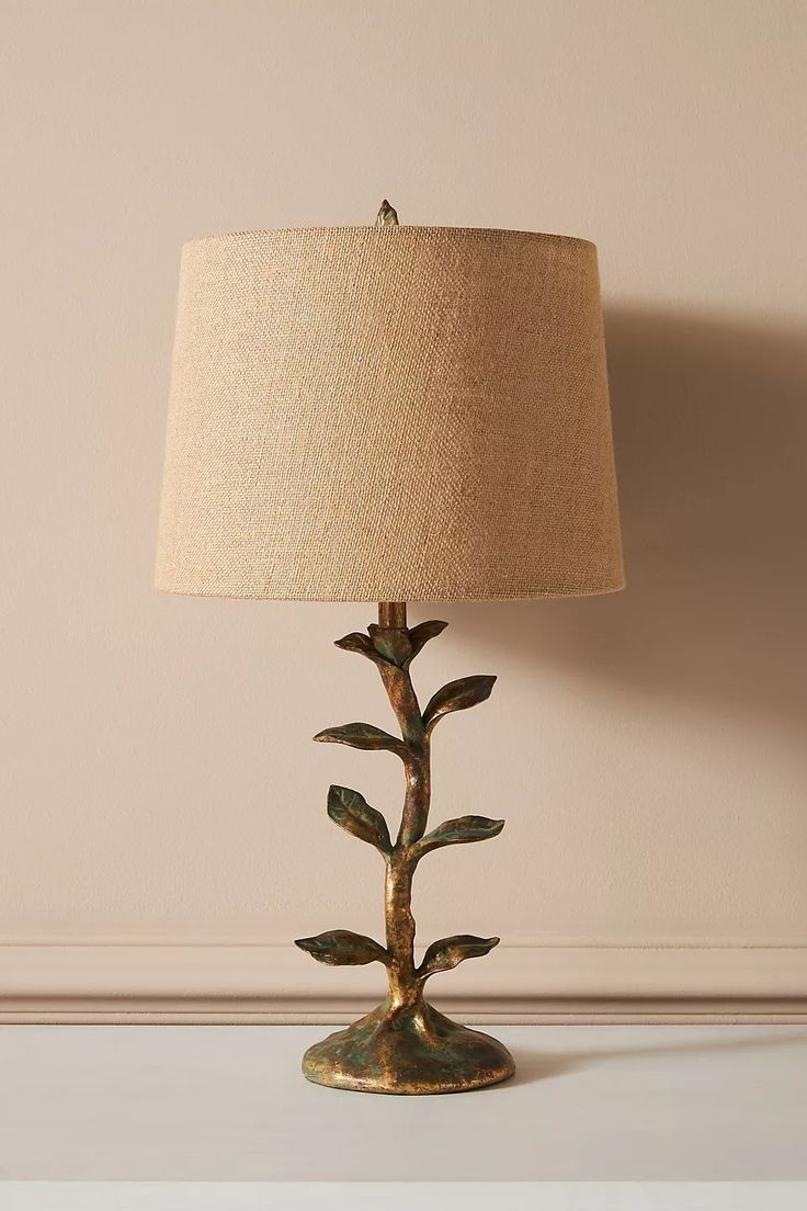 a lamp that is sitting on top of a table next to a white wall with a brown shade