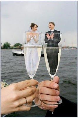 two people holding up champagne flutes in front of the water