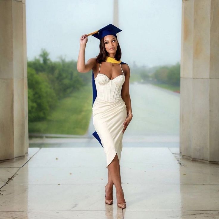 a woman in a graduation cap and gown posing for the camera with her hand on her hip