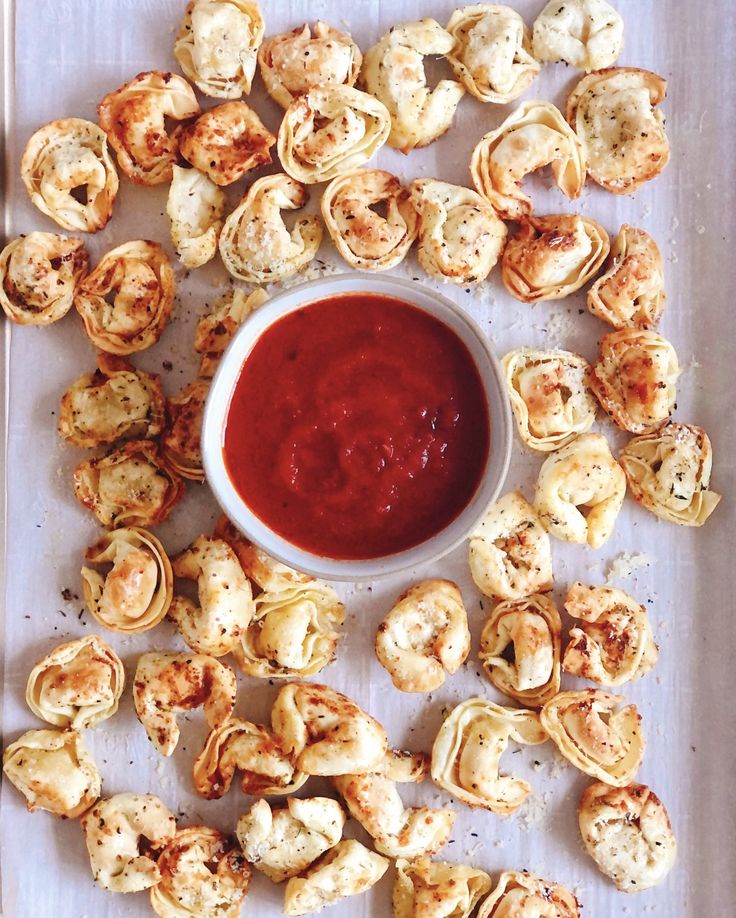 a white plate topped with mini pizzas next to a bowl of ketchup