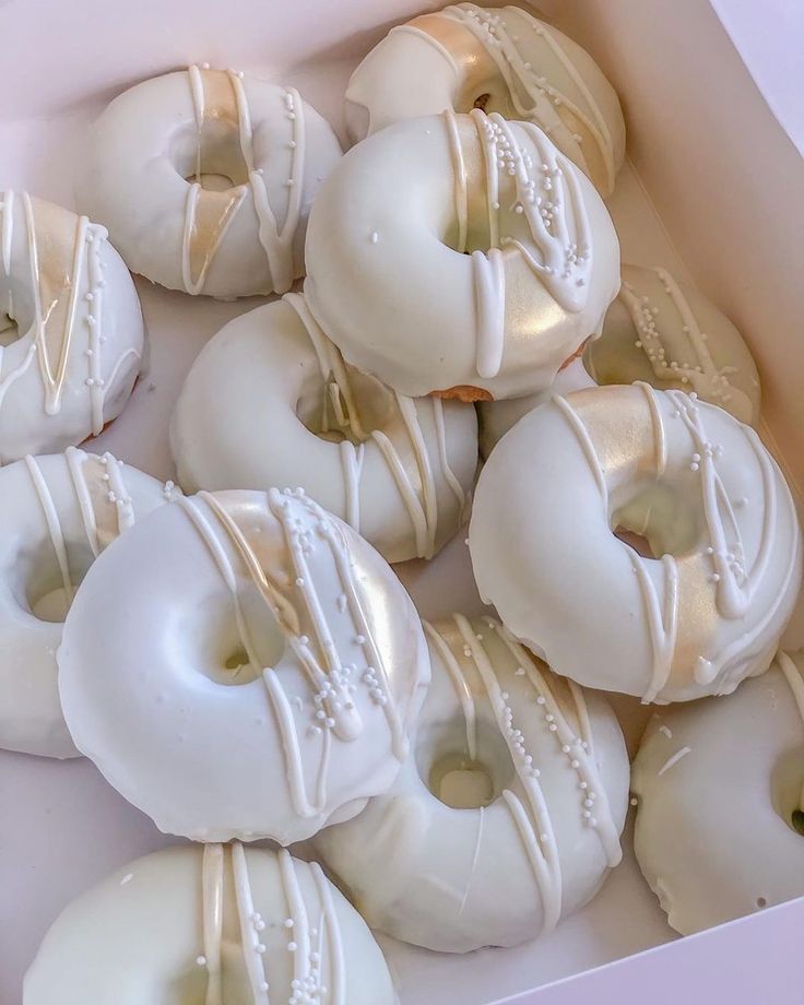 a box filled with white frosted donuts covered in icing and beading