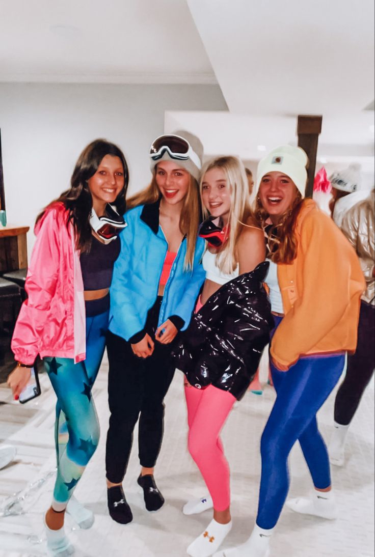 four young women posing for a photo in front of a mirror with skis on