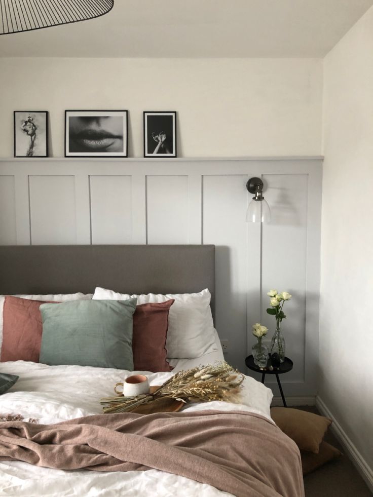 a bed with pillows and blankets in a bedroom next to two pictures on the wall