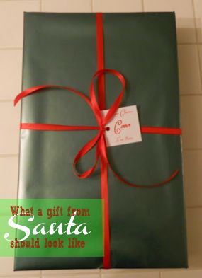 a gift wrapped in green paper with a red ribbon and tag that says, what a gift from santa should look like