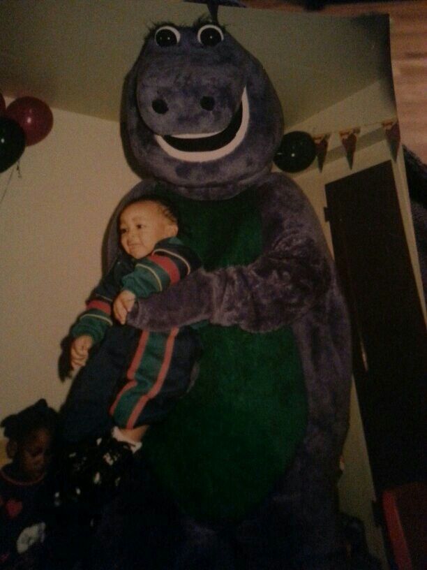 a man holding a small child in front of a large stuffed hippopotamus