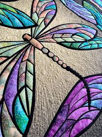 a stained glass dragonfly sitting on top of a tablecloth covered in purple, blue and green colors