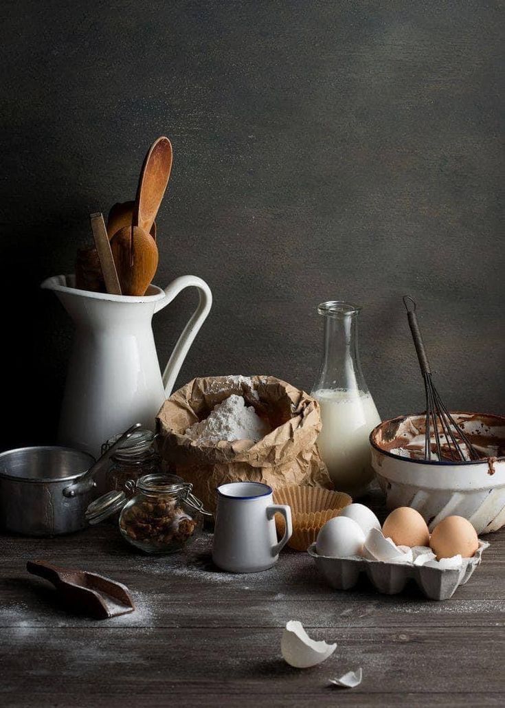 an assortment of ingredients including eggs, milk and other items on a table with spoons