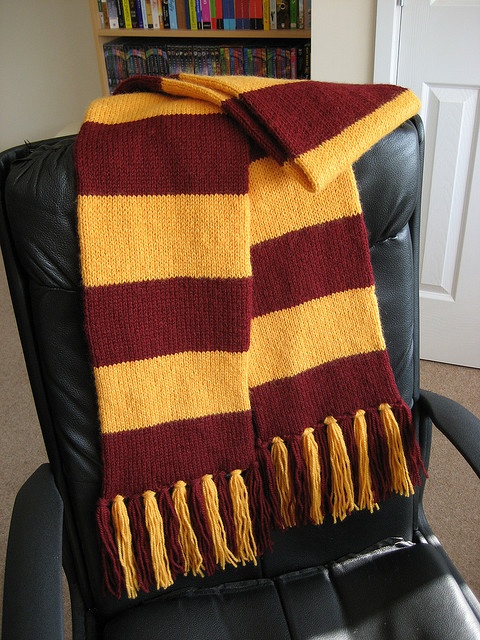 a blanket sitting on top of a black chair in front of a book shelf filled with books