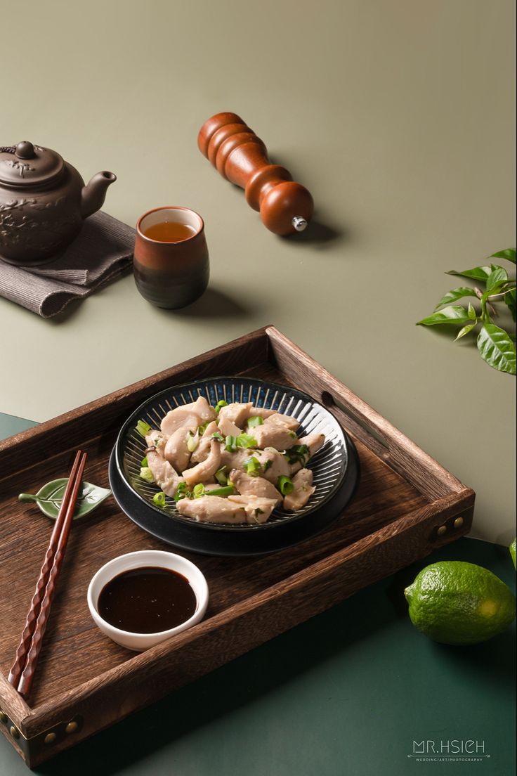 a wooden tray topped with food and chopsticks on top of a green table