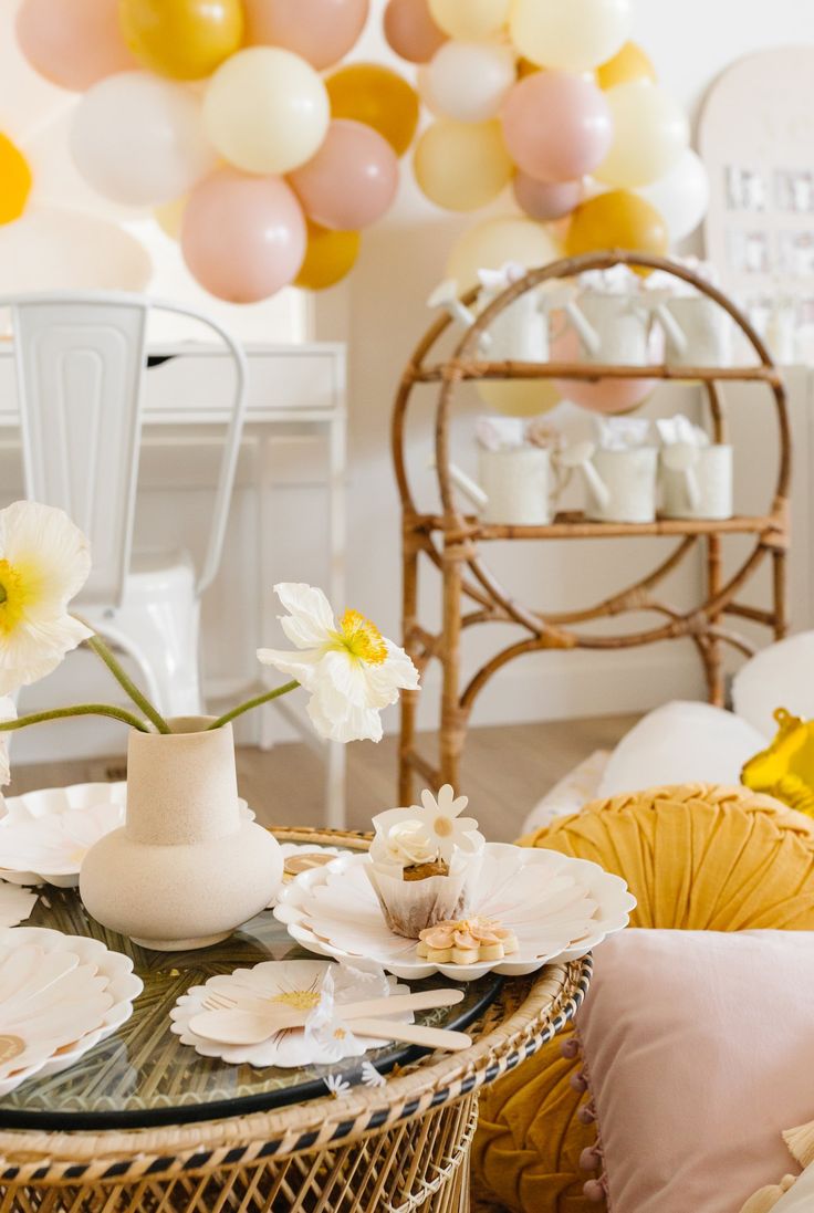 a table with plates and flowers on it in a room decorated for a baby's first birthday