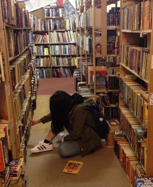 two people kneeling down in front of a library filled with books