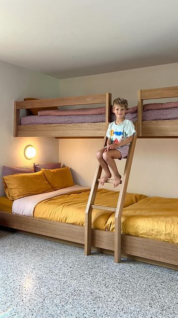 a young boy sitting on top of a bunk bed in a room with yellow bedspreads