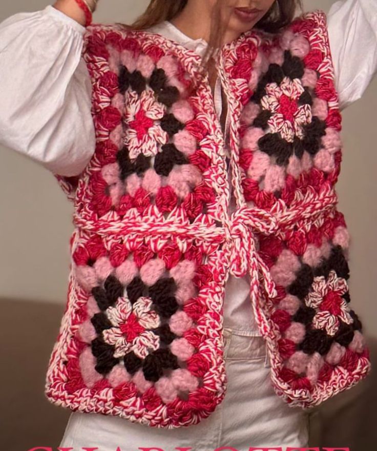 a woman wearing a red and white crocheted vest with flowers on the front