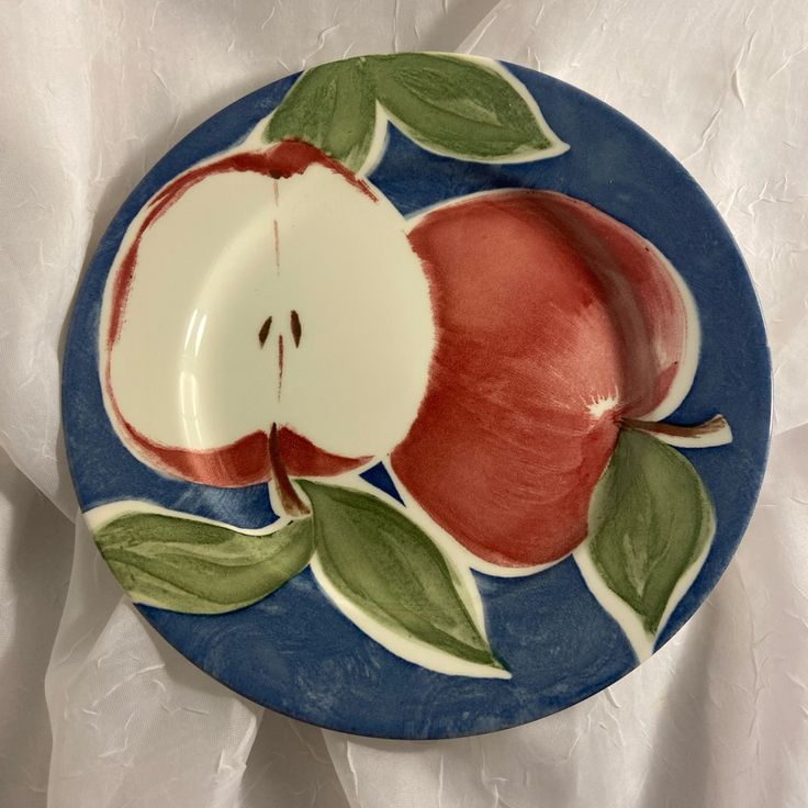 an apple on a blue plate with green leaves