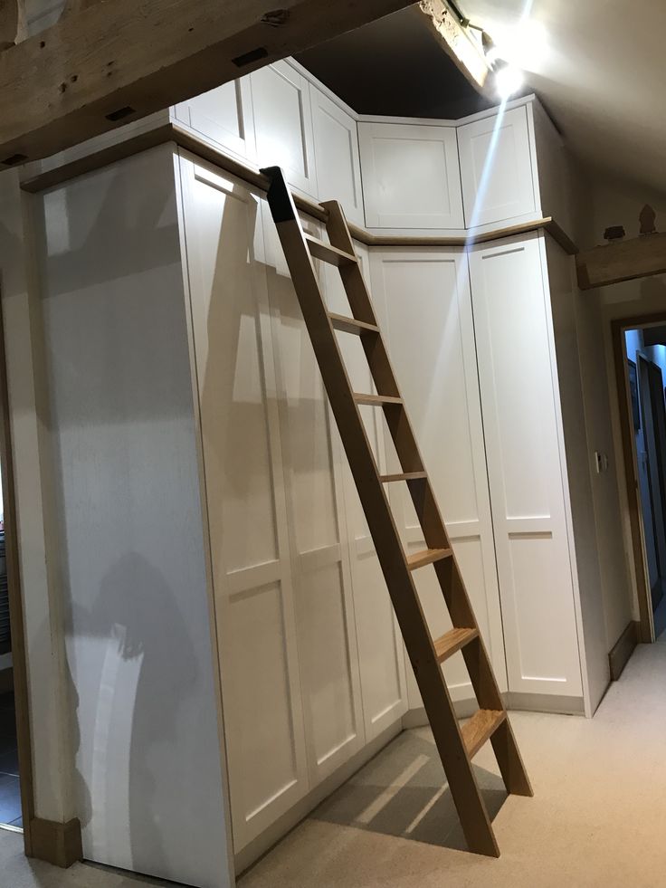 a ladder leaning up against the wall in a room with white cupboards and cabinets