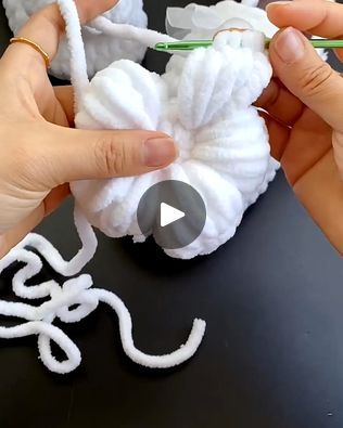 someone is crocheting yarn on top of a piece of white material with scissors