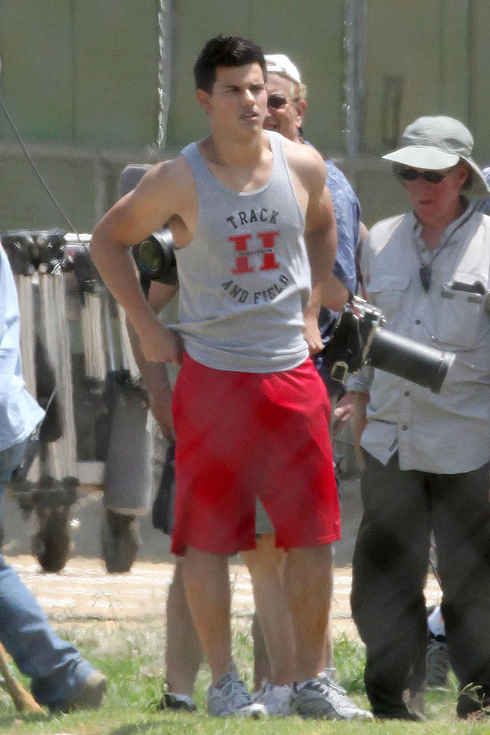 a man standing in front of a camera on top of a field with other people behind him