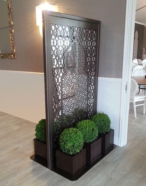 a room divider with two planters on each side and some green plants in the middle