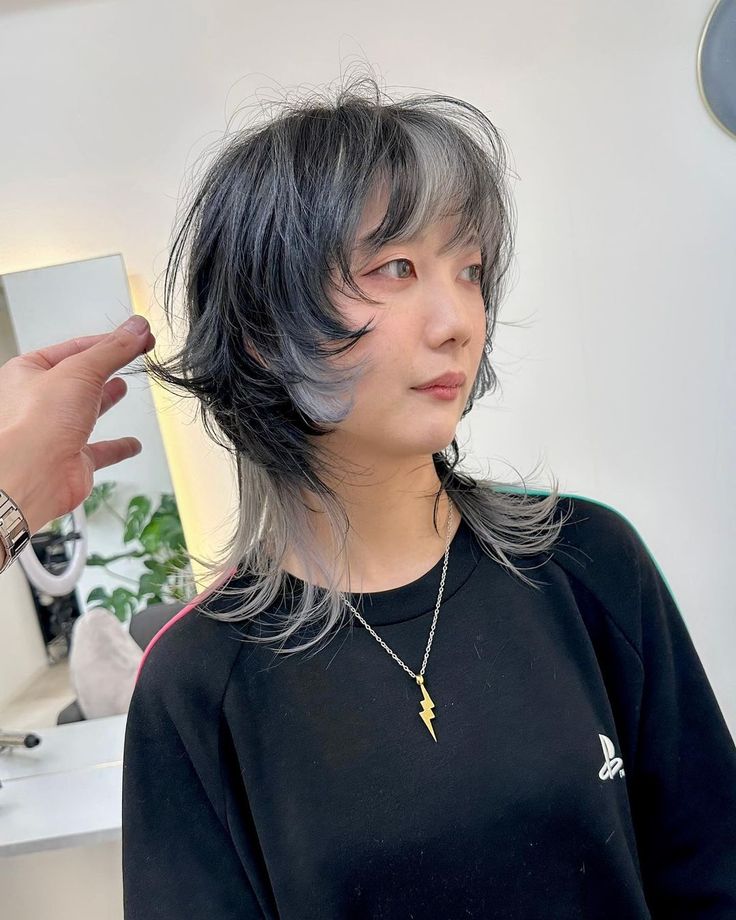 a woman with grey hair is getting her hair cut by a man in a black shirt