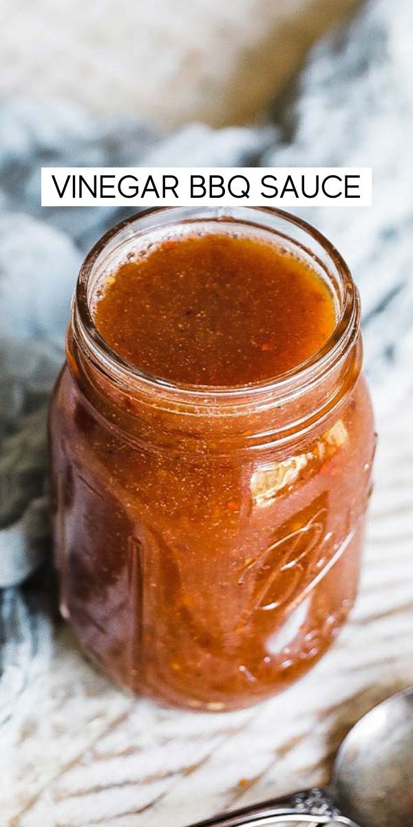 a jar filled with bbq sauce sitting on top of a table next to a spoon