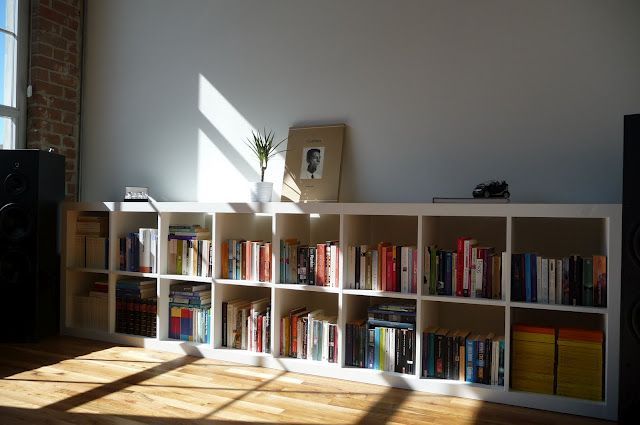 a bookshelf filled with lots of books next to a window in a room