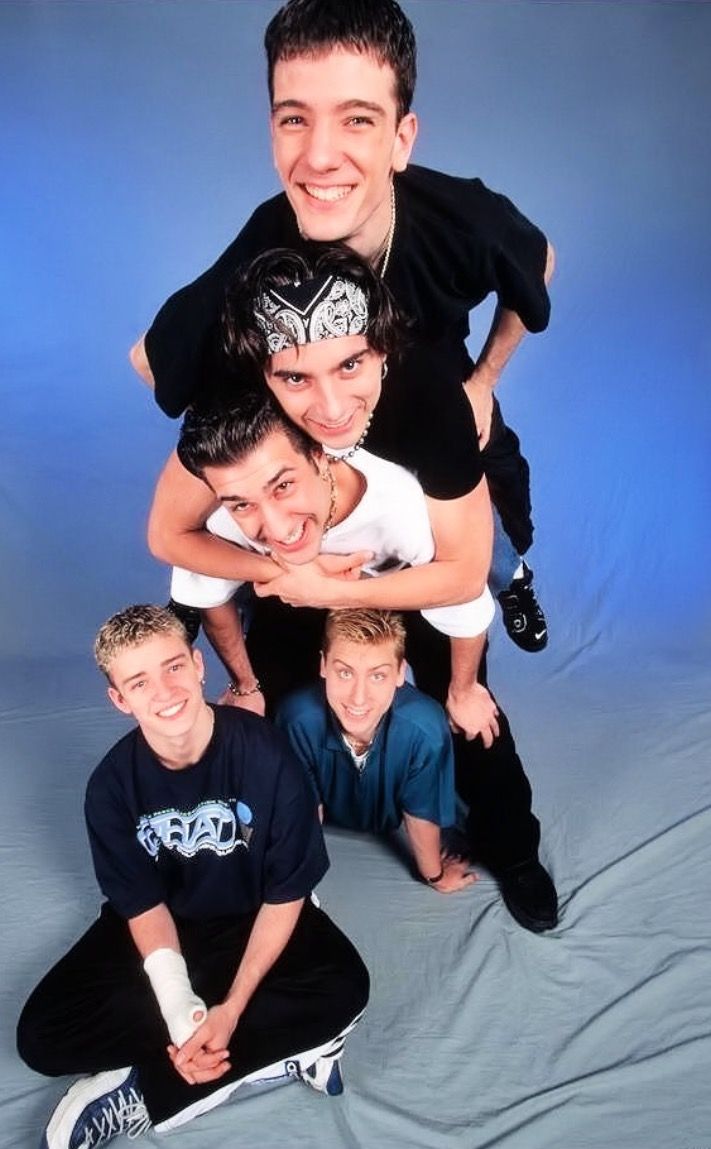 a group of young men standing next to each other on top of a blue background