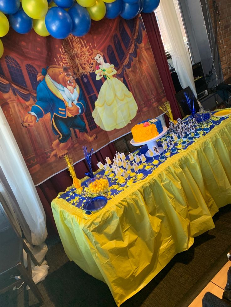 the table is set up for a beauty and the beast themed birthday party with balloons