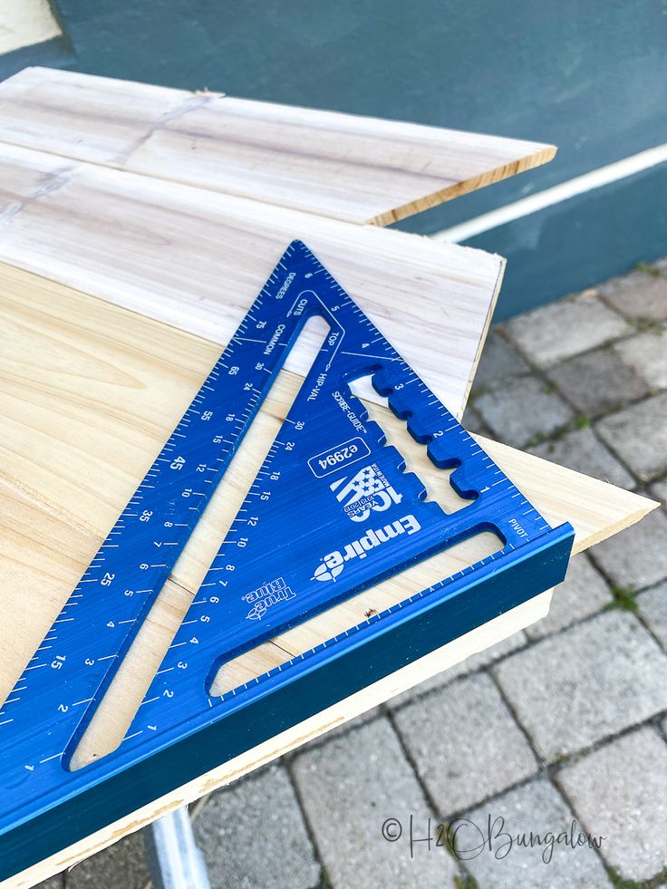 a wooden table topped with blue rulers and a pair of plywood shears on top of it