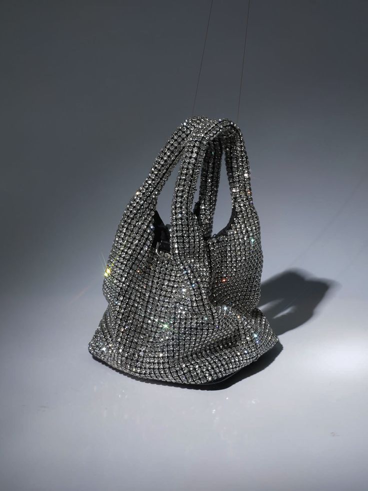 The Bellatrix Crystal Bucket Bag In Silver inspired by starry nights! It is a stylish handmade medium-size bucket handbag. Hand-crafted in high-quality rhinestone crystals, it completes an elegant yet chic look that will turn heads and make you the party star. The shiny handbag comes with a detachable silver chain strap, allowing you to wear it hands-free or as a clutch.     Material: PU   5.9inch / 15cm diameter (dimensions approx.) Luxury Bucket Bag For Party, Luxury Silver Bucket Bag For Evening, Luxury Silver Bucket Bag For Party, Evening Bucket Bag With Rhinestones, Evening Bucket Bags With Rhinestones, Luxury Handheld Bucket Bag For Party, Elegant Silver Bucket Bag For Evening, Elegant Bucket Bag With Rhinestones, Elegant Rhinestone Bucket Bag