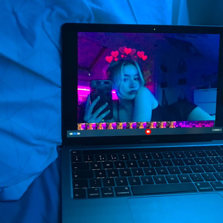 an open laptop computer sitting on top of a blue sheet covered bed with the image of a woman's face