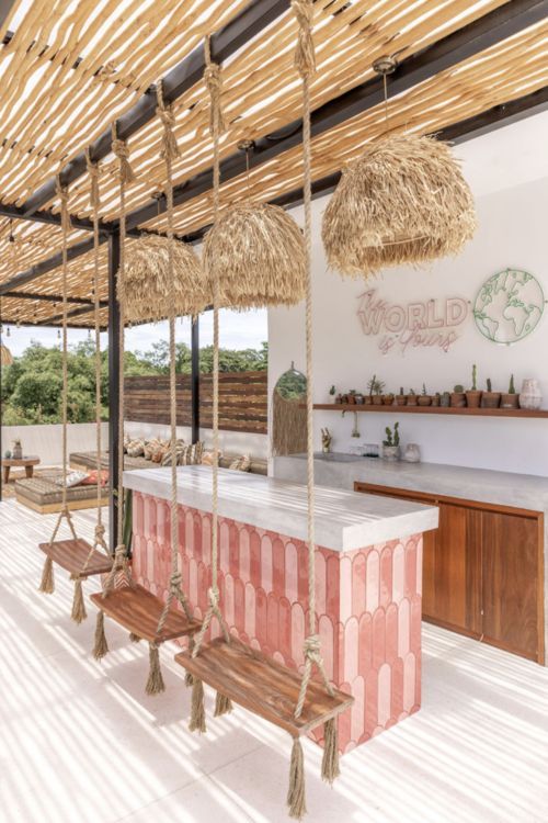 an outdoor bar with straw umbrellas hanging from it's ceiling and benches on the side