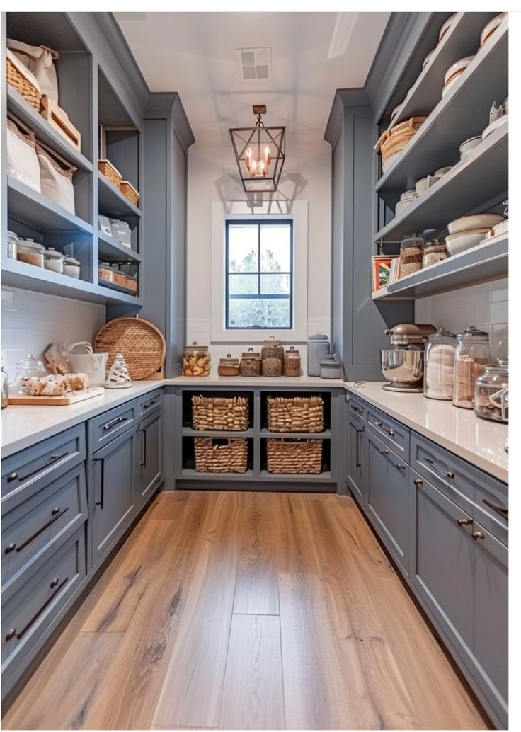 a large kitchen with gray cabinets and wooden floors is pictured in this image, there are baskets on the counter