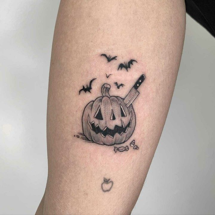 a black and white photo of a halloween pumpkin with a knife in it's mouth