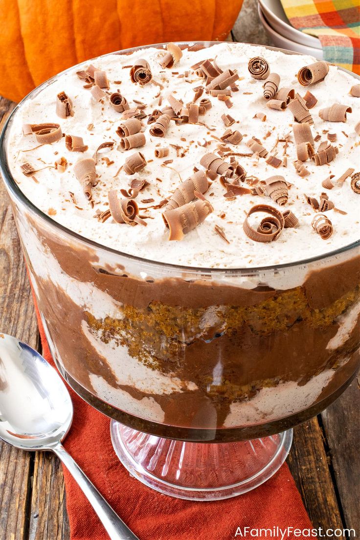 a dessert in a glass dish with whipped cream and chocolate chips on top, sitting on a wooden table