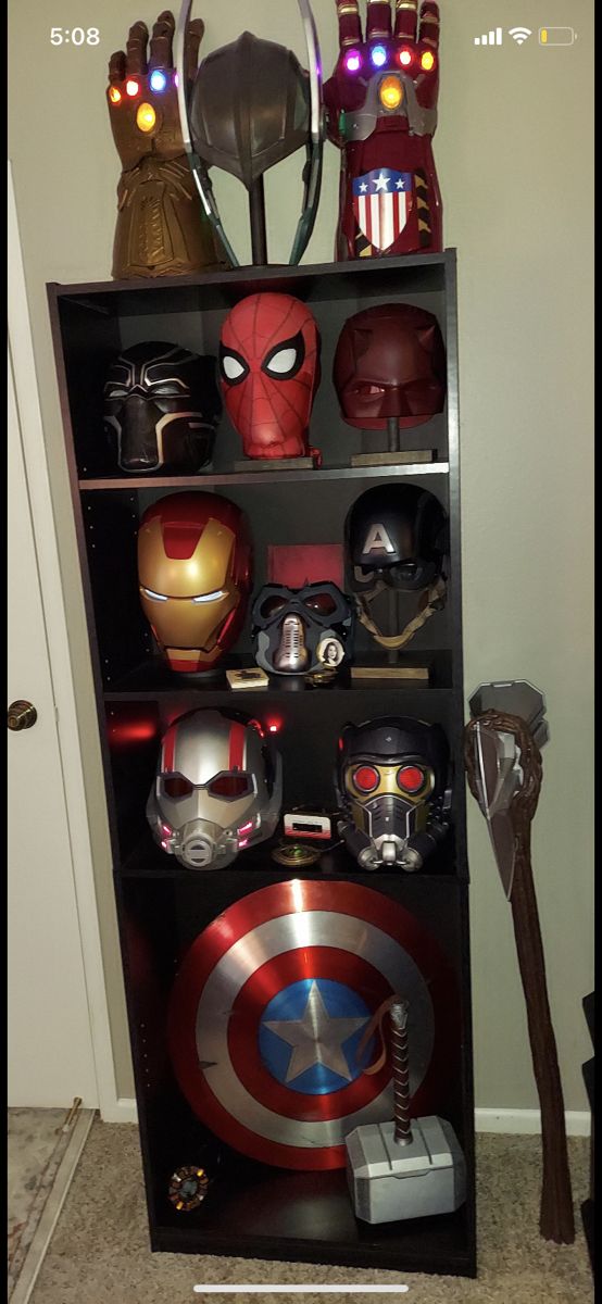 a book shelf filled with avengers masks on top of it