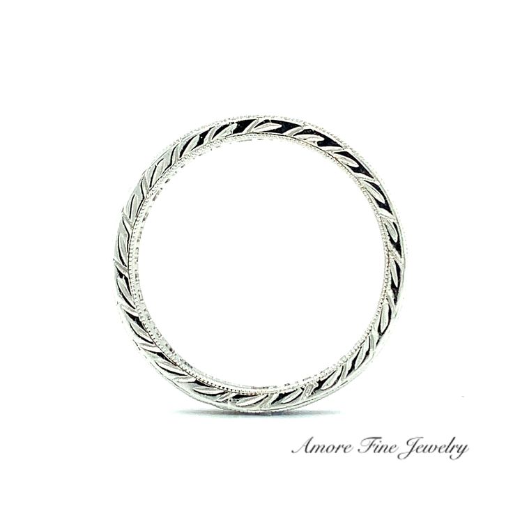 a white gold wedding ring with braiding on the sides and an inscription underneath it