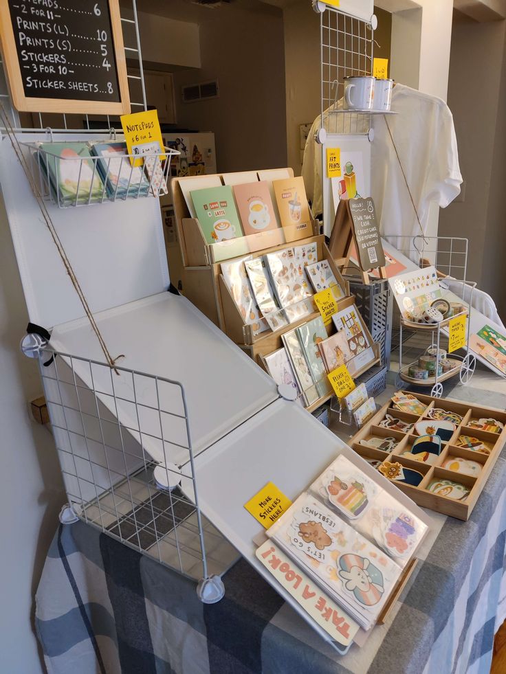 the table is covered with many cards and other items for sale at the market stall