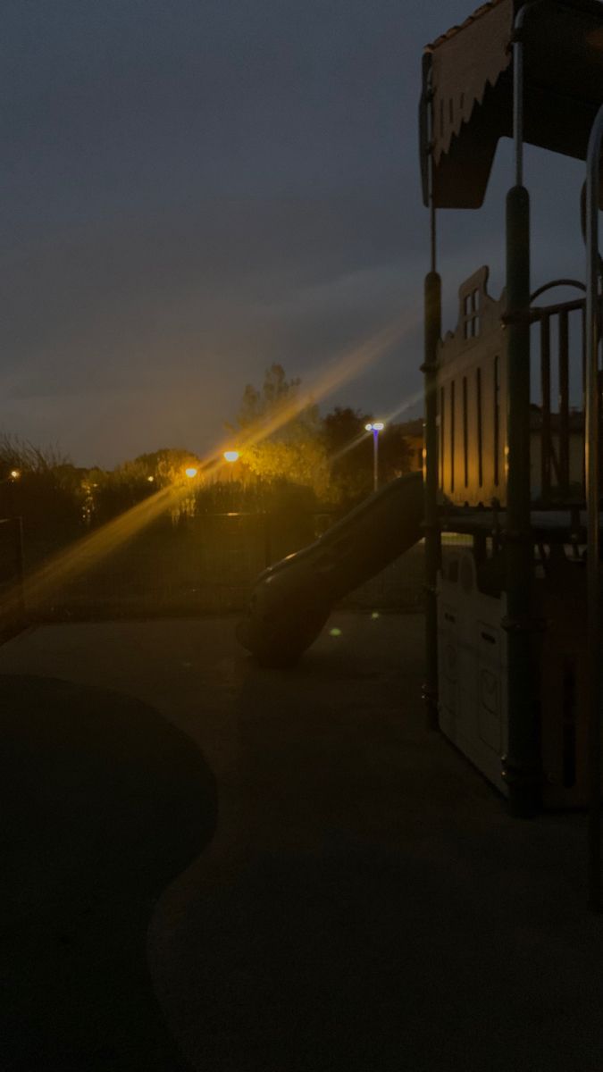 an empty playground at night with the sun shining down on it's play area