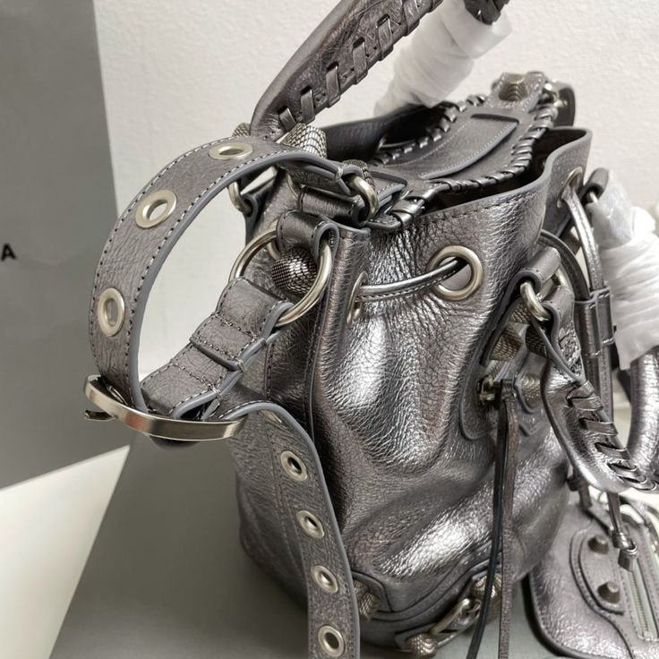 Balenciaga 's popular "Le Cagole" series is a modern interpretation of its "City" handbags - reshaped into a bucket bag design to inject a new soul into it. The large size adds two round top handles, combining classic and Modern trends are perfectly integrated. On the basis of retaining the original DNA of the motorcycle bag's flat rivets, delicate buckles and tassel zippers, it adds adjustable woven shoulder straps and a cute and playful heart-shaped mirror, which perfectly softens the neutral temperament of the original version. .
Original burst sheepskin imported from Italy (explosion fine lines can be seen)
Large Size: 30*23*17cm Chic Bucket Bag With Silver-tone Hardware For Daily Use, Luxury Chic Bucket Bag With Silver-tone Hardware, Chic Bucket Bag With Silver-tone Hardware, Modern Bucket Bag With Silver-tone Hardware, Luxury Bucket Bag With Silver-tone Hardware, New Soul, Dumpling Bag, Shaped Mirror, Motorcycle Bag