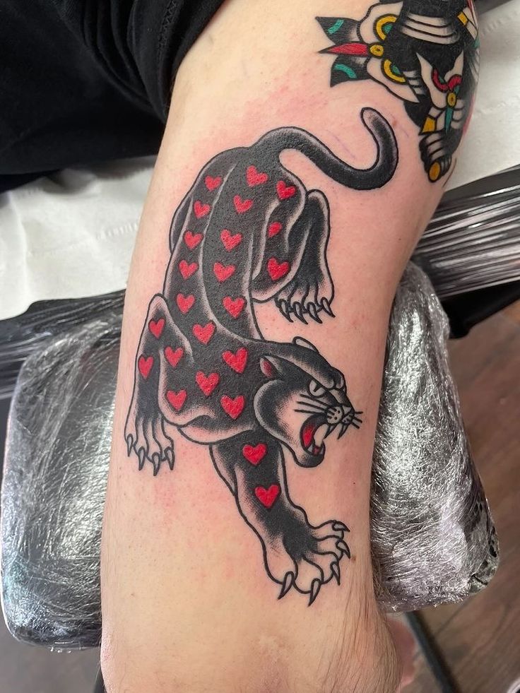 a black and red tattoo on the leg of a person's arm with hearts in the shape of a dragon