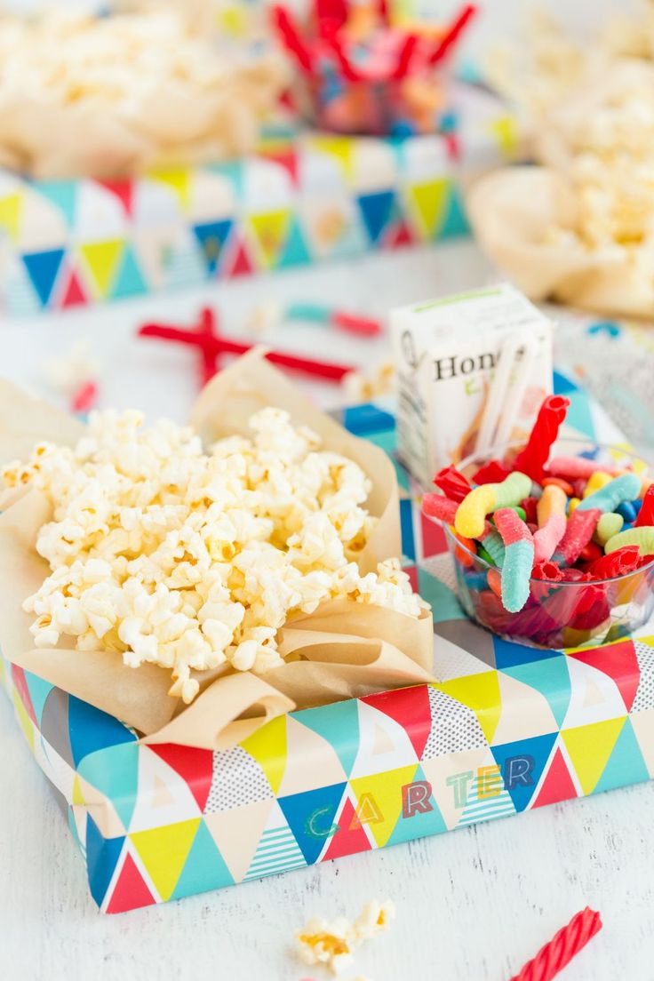 popcorn and other snacks are sitting on the table with colorful paper streamers around them