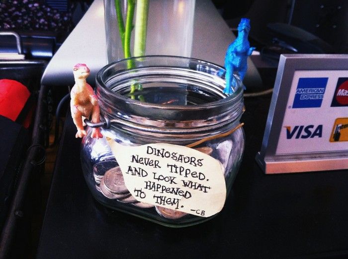 a glass jar filled with money sitting on top of a desk next to a sign