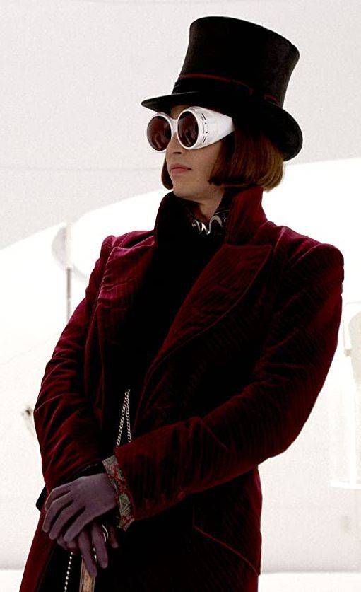 a woman in a red coat and black hat with goggles on her face, standing outdoors