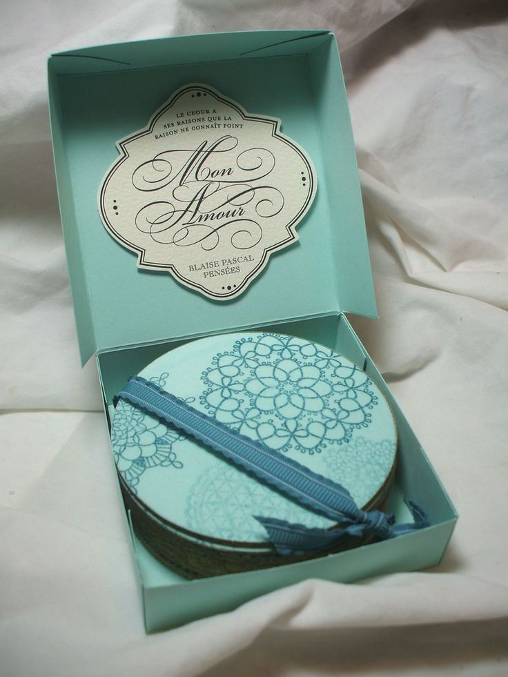 an open box with a cake in it on a white sheeted surface, next to a blue ribbon