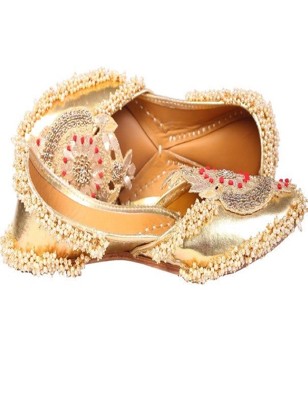 Bringing class to your wardrobe with our beautifully handcrafted 'golden Crown' juttis. Glossy silver based adorned with palmette like motif that is embroidered with gotapatti and silver dabka work. We added bunches of ivory beads to give it a fuller look. Asymmetrical neckline adds an extra glamour to the whole jutti. You can pair these up with an embroidered lehenga or saaree in contrasting color for a party or festive look! Color: Gold Fabric: Faux Leather Upper- Silver faux Leather - leather Gold Embellished Traditional Wear For Reception, Festive Gold Embellished Traditional Wear, Gold Embellished Traditional Wear For Festivals, Gold Traditional Wear For Reception And Navratri, Gold Traditional Wear For Festive Reception, Festive Gold Traditional Wear For Reception, Gold Traditional Wear For Reception And Festivals, Gold Traditional Wear With Gold Embroidery For Festive Occasions, Silver Traditional Wear With Zari Work For Transitional Season